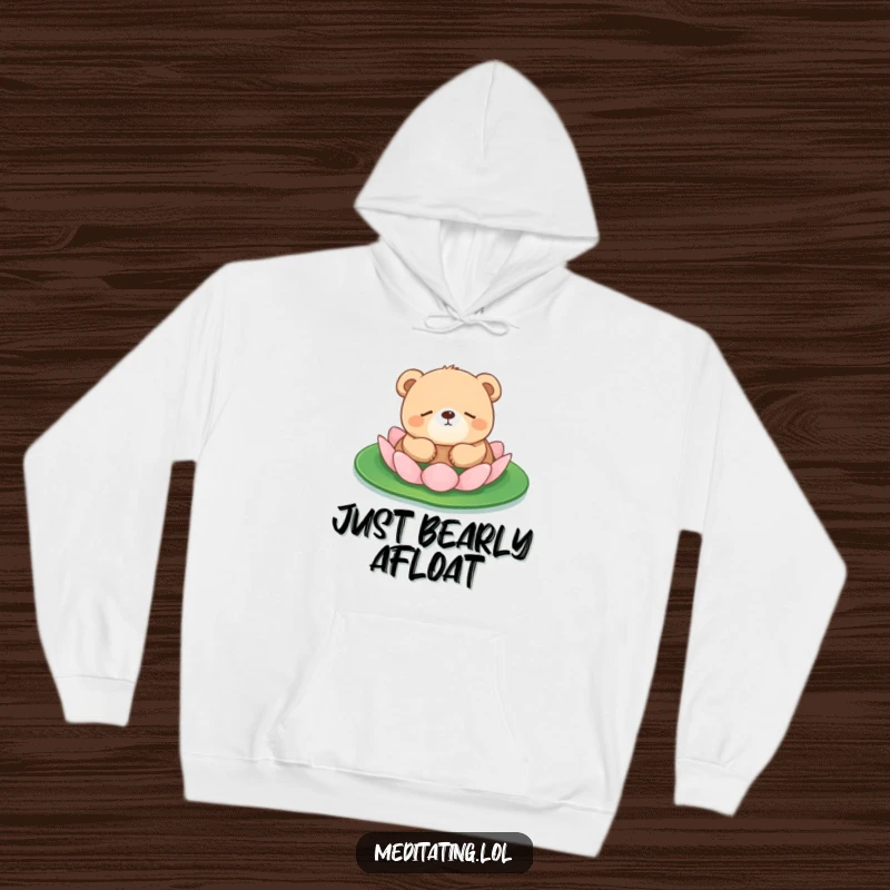 Funny bear cub hoodie showing a sleepy bear cub floating serenely on a lily pad, offering cozy peace.